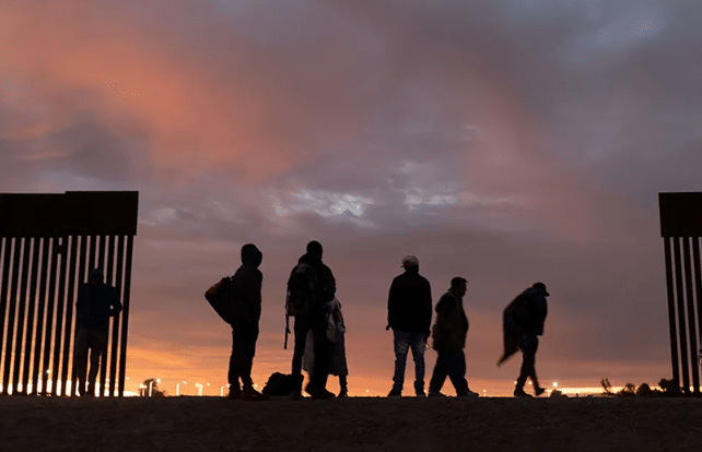 Grupo de migrantes frente al muro fronterizo entre Estados Unidos y México