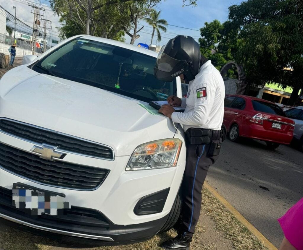 Elemento de Tránsito sancionando un vehículo mal estacionado.