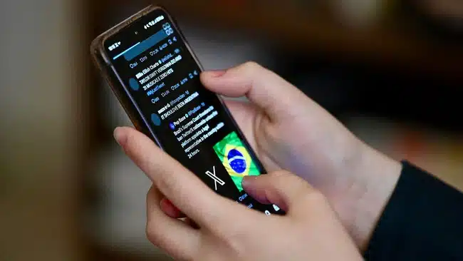 Una persona observa desde el celular noticia sobre el bloque de X en Brasil