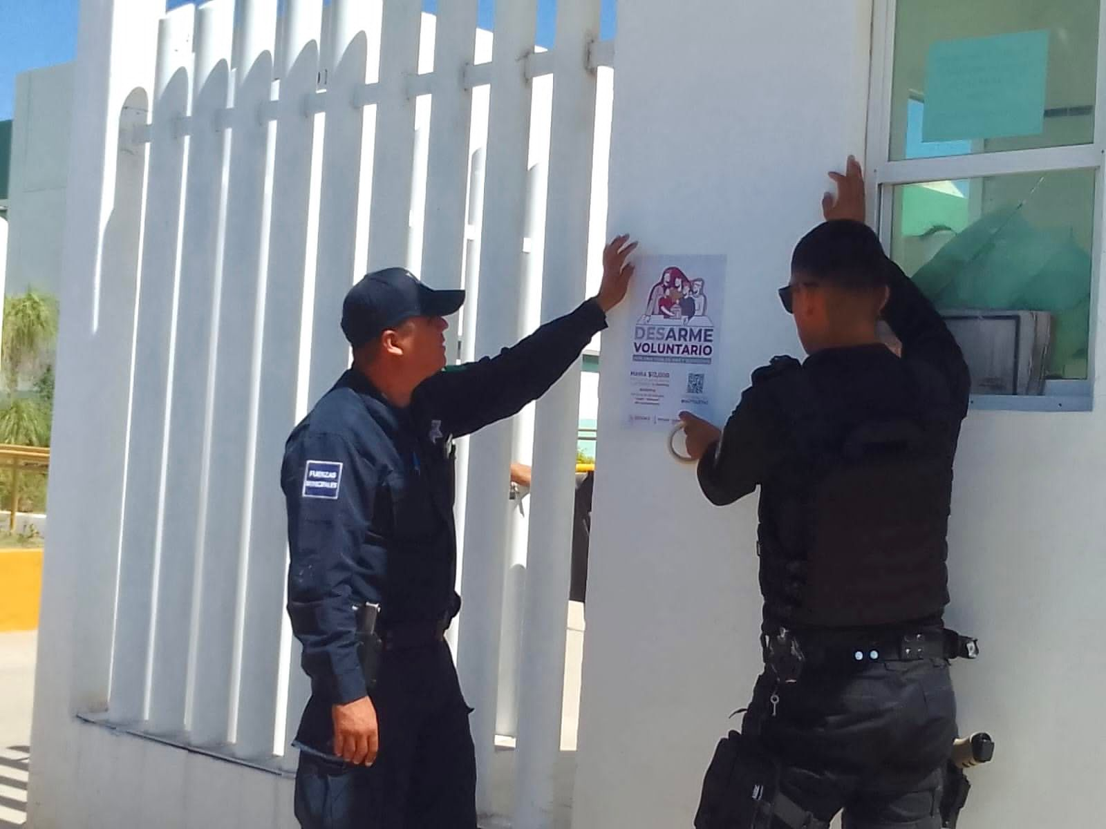 Elementos de seguridad colocando un volante para invitar a la población a participar en el Desarme Voluntario en Ahome.