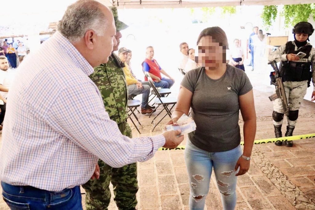 Alcalde Rolando Mercado entregando dinero en efectivo a una ciudadana que participó en el Desarme Voluntario.