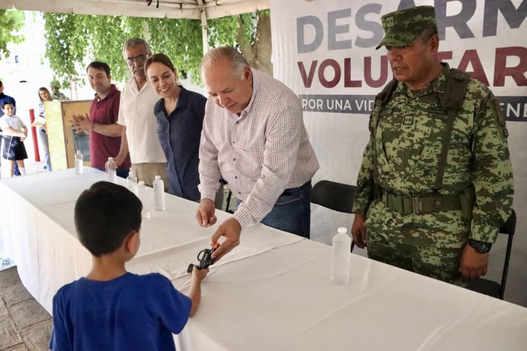 Un pequeño entregando su arma de juguete en el Desarme Voluntario.