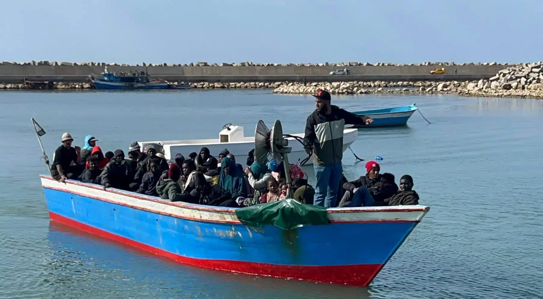 Migrantes arriba de un bote de la Guardia Costera de Yibuti