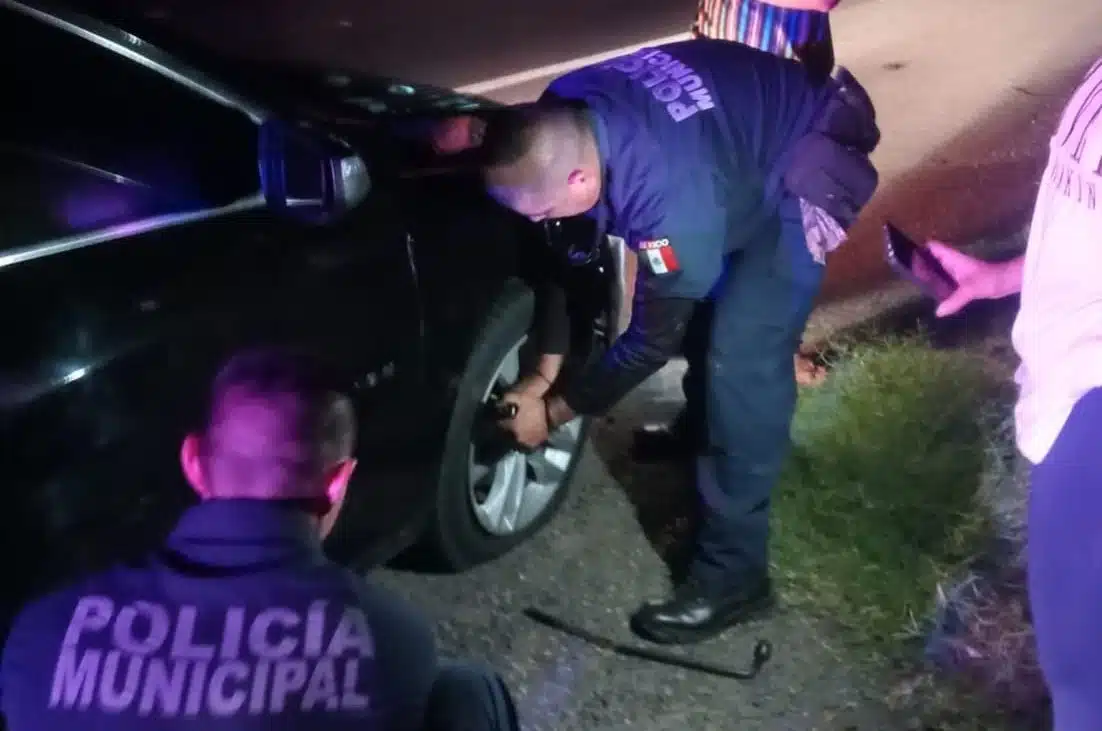 Agentes de la policía municipal cambian una llanta de un carro en la carretera México 15