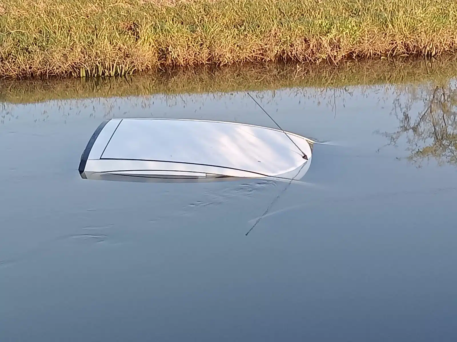 Techo de un carro que sobresale dentro de un canal de riego