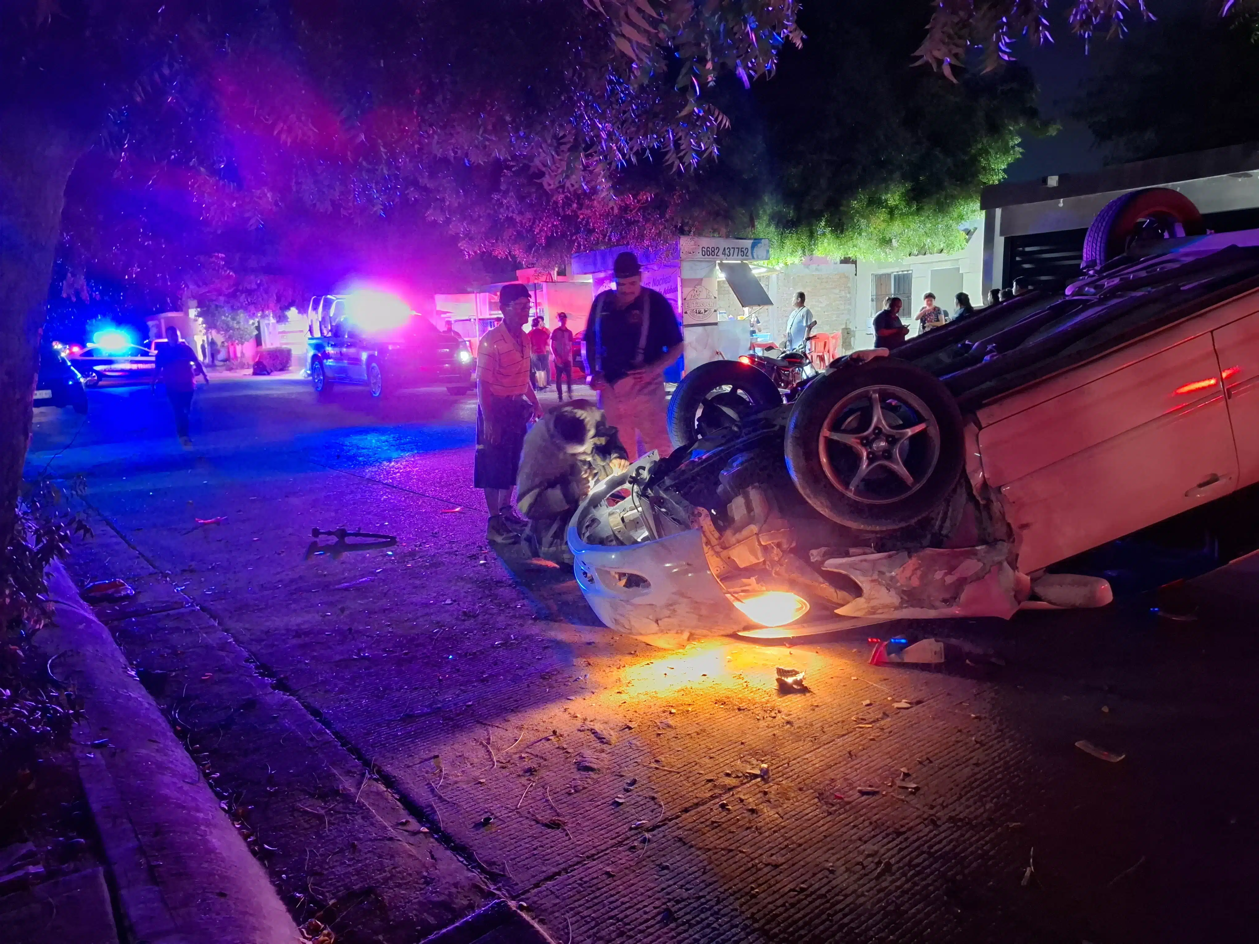 Vehículo volcado, mientras elementos de seguridad y testigos se encuentran en el área del accidente vial.