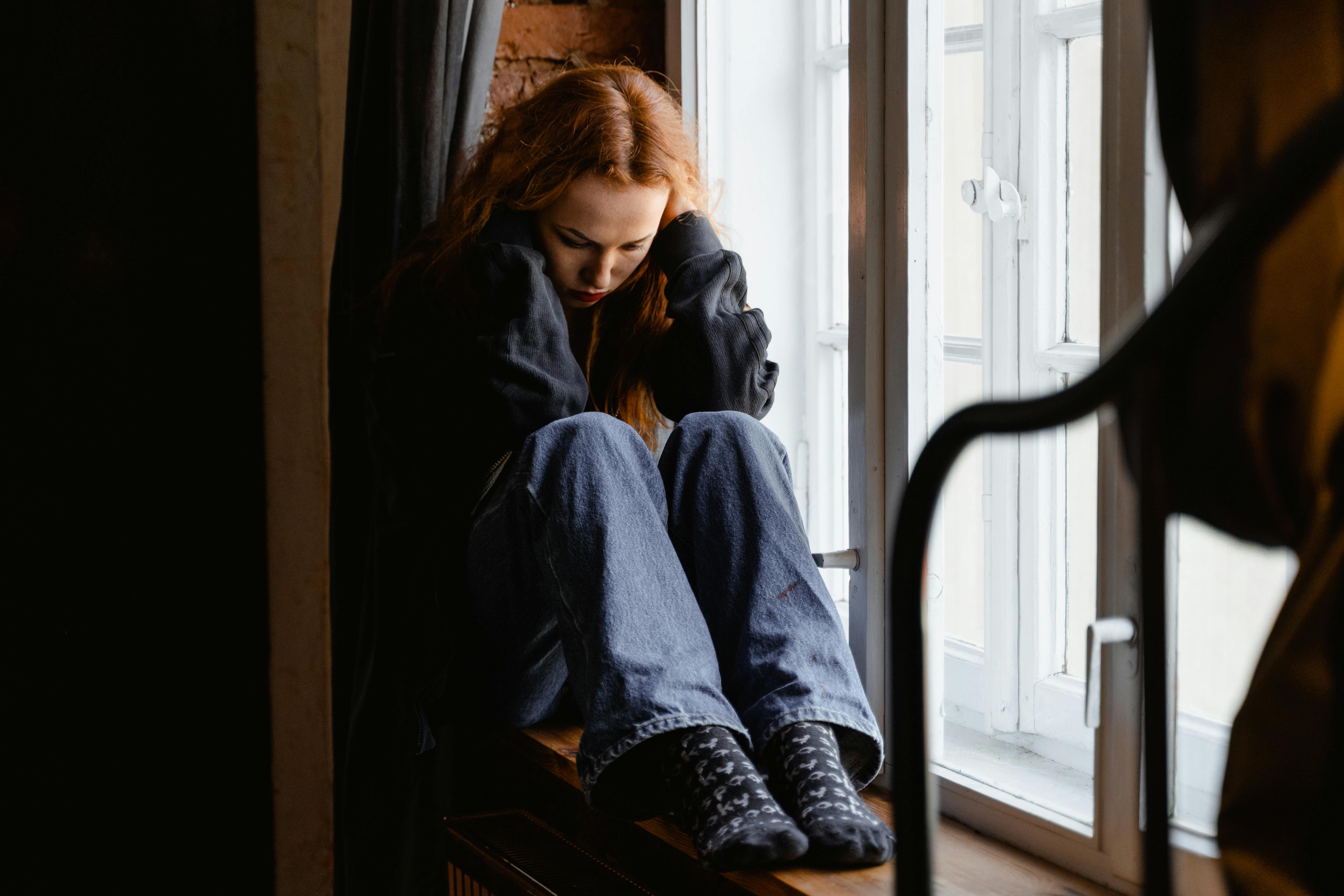 Mujer triste sentada en una ventana