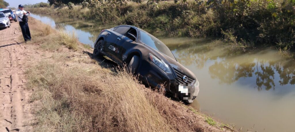 Automóvil Nissan Altima negro, modelo 2018, ladeado sobre el borde derecho del canal.