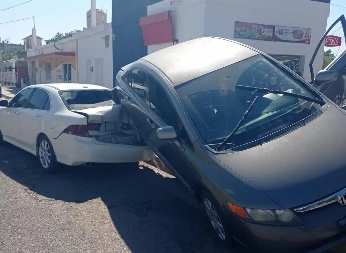 Vehículo encaramado encima de otro. Ambos con daños en la carrocería.