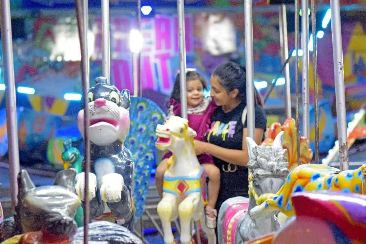 Madre e hija en el carrusel durante la tradicional feria de El Fuerte