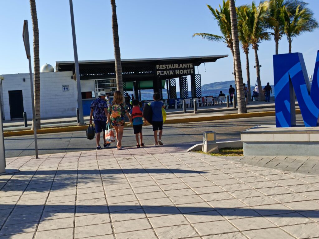 Turistas caminan hacia el restaurante Playa Norte de Mazatlán