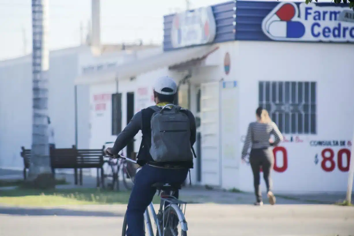 Ciclista transitando con un abrigo puesto por las calles de Los Mochis