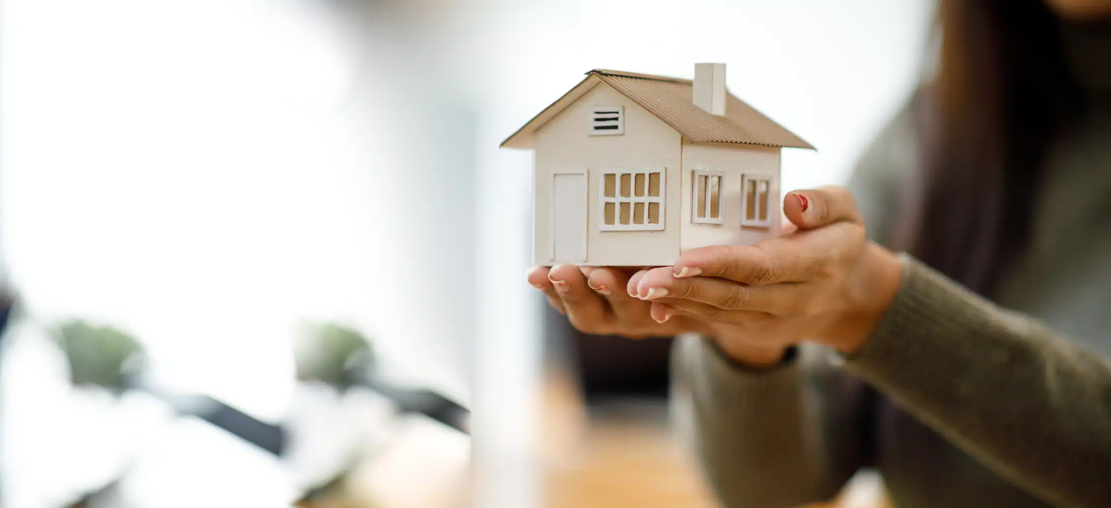 Una persona sosteniendo una maqueta de una casa