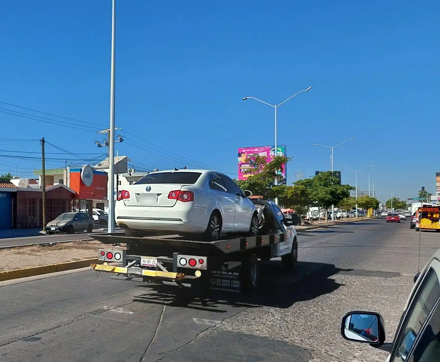 Automóvil Volkswagen Jetta de color blanco siendo trasladado en una grúa tras el accidente vial en Los Mochis.