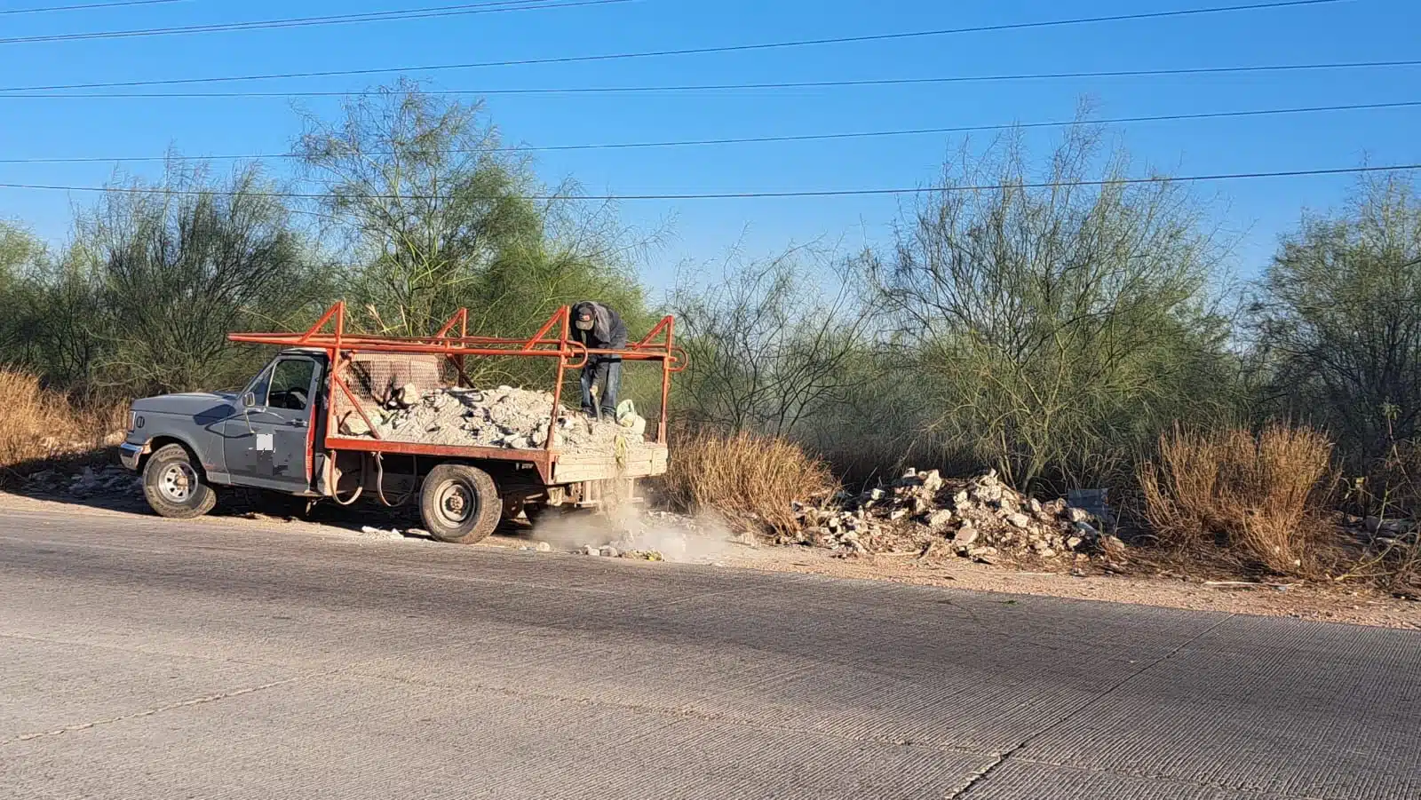 Civil tirando escombro en la orilla de la carretera Mochis-Topolobampo.