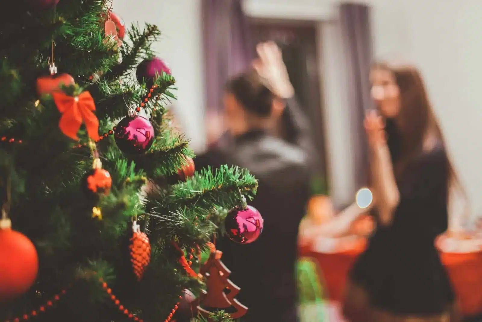 Árbol de Navidad y al fondo unas personas conviviendo.