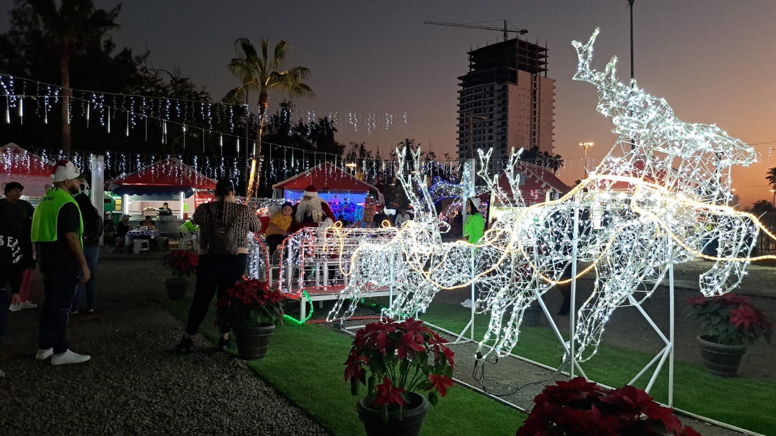 Familia tomándole una foto a su hijo con Santa Claus en la Villa Navideña.