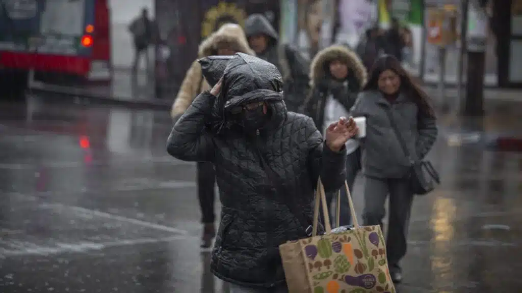 Personas abrigadas por el frío y la lluvia