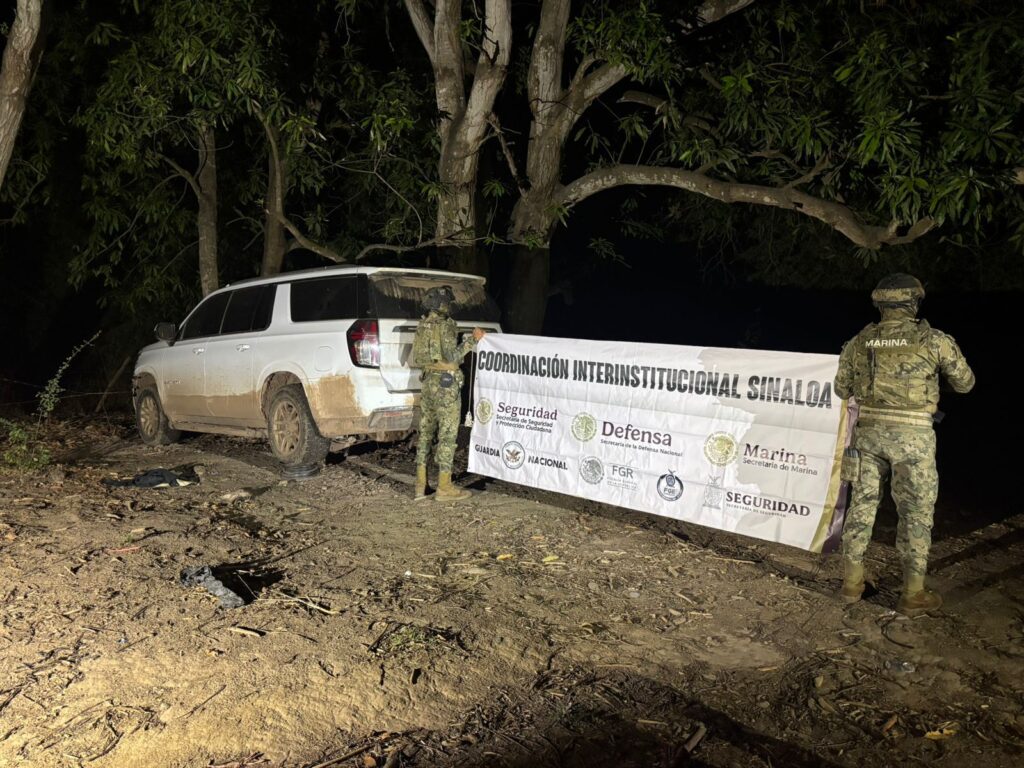 Militares sosteniendo una pancarta junto a uno de los vehículos asegurados.