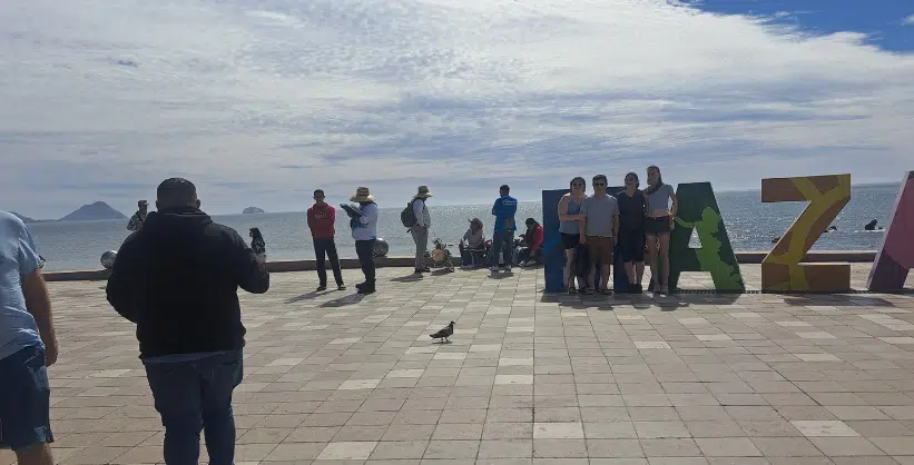 Turistas toman una foto a toman una foto los monigotes del Carnaval de Mazatlán