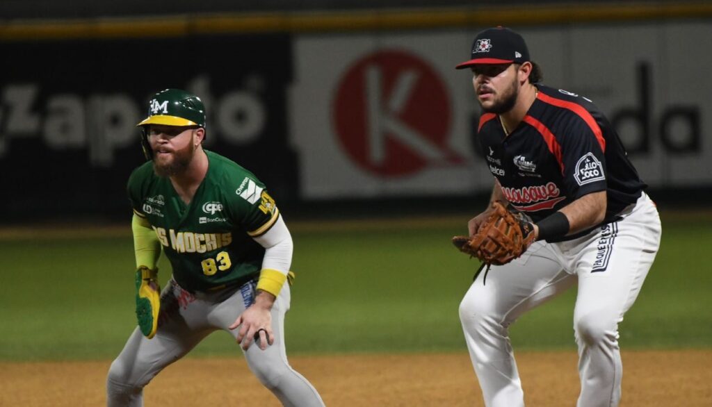 Eric Filia corriendo por primera base y siendo custodiado por Roberto Ramos