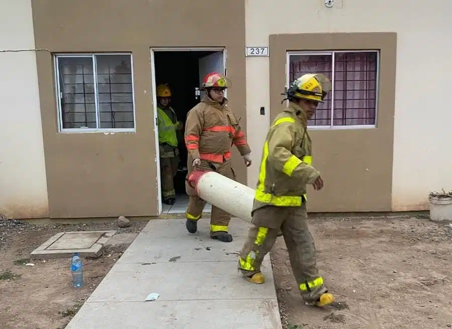 Bomberos de Guasave sacando el cilindro de gas de la vivienda.