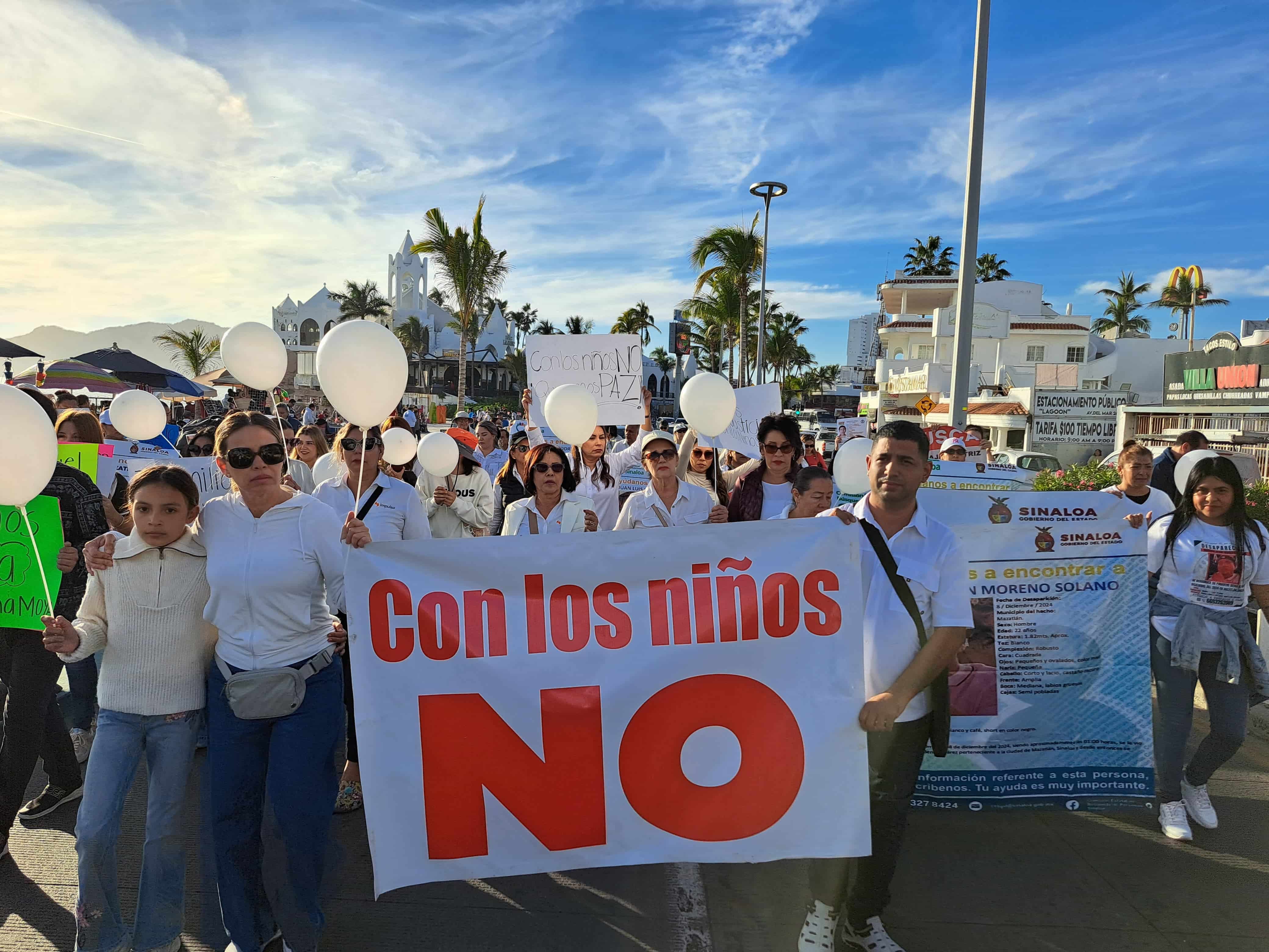 Ciudadanos marchando por el malecón de Mazatlán para protestar por el atentado a una familia de Culiacán.