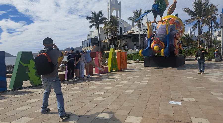 Turistas toman una foto a toman una foto los monigotes del Carnaval de Mazatlán