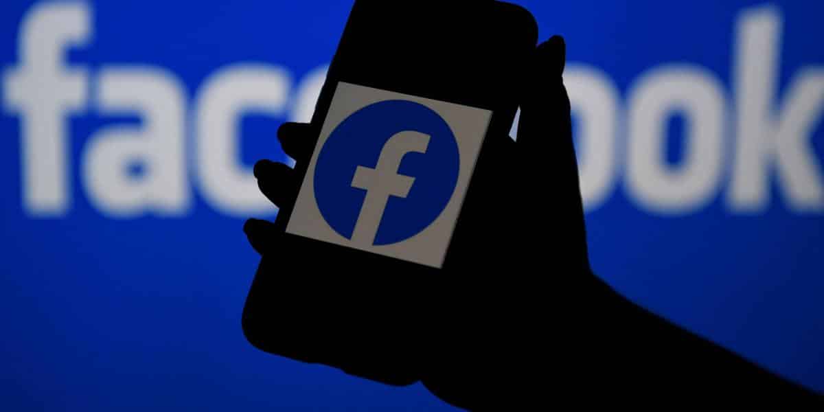 Mano sosteniendo un celular con la app de Facebook