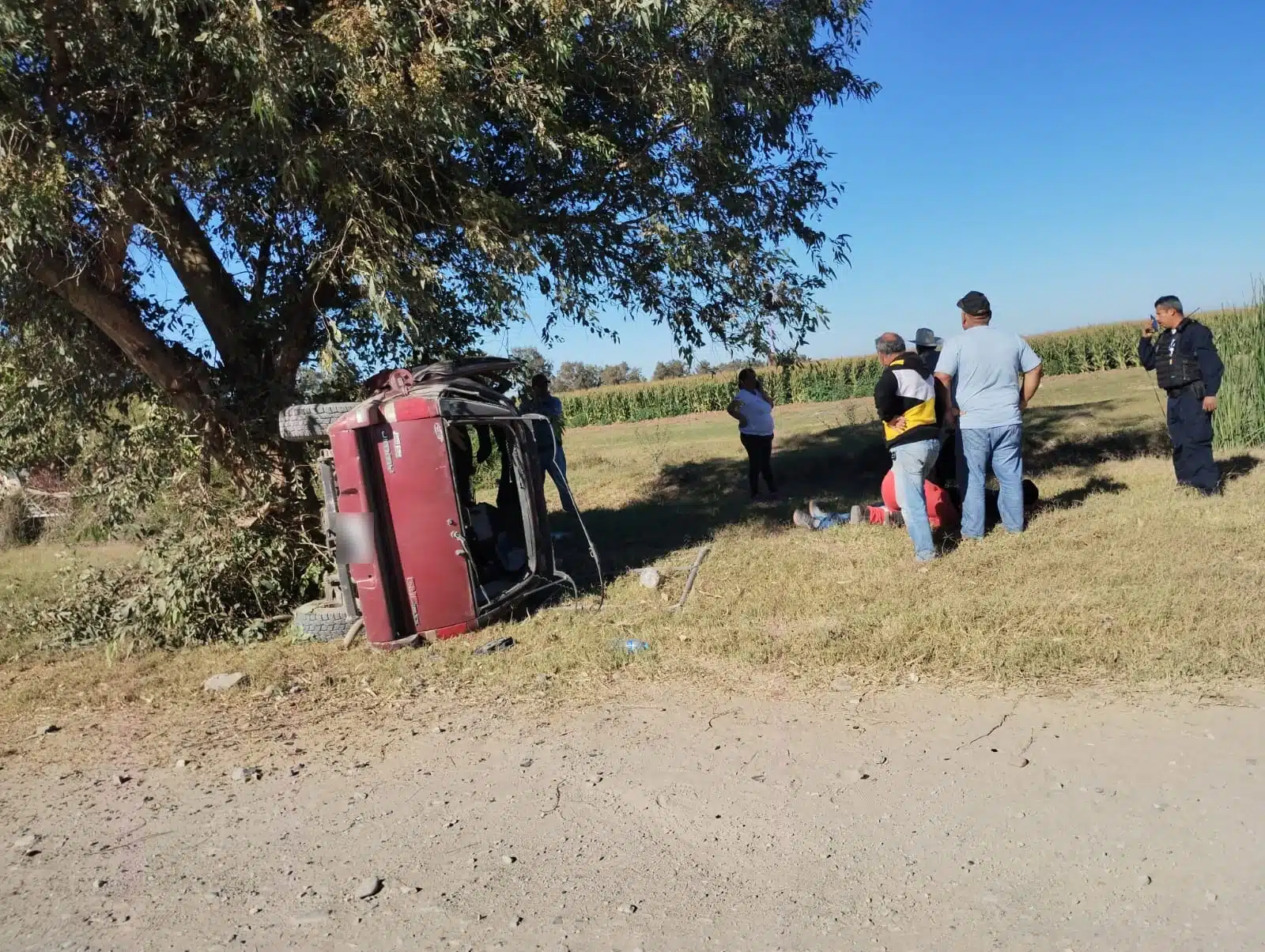 Camioneta volcada sobre un costado y paramédicos de Cruz Roja auxiliando a la persona herida.