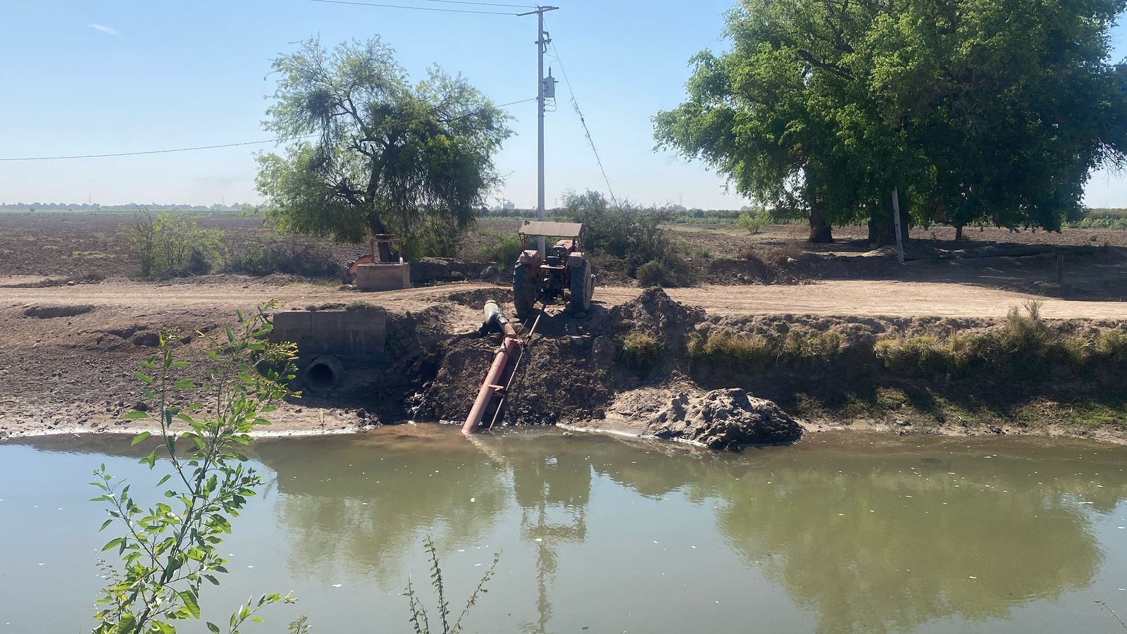 Tractor extrayendo agua con una bomba charquera del canal Sevelbampo, en Ahome.