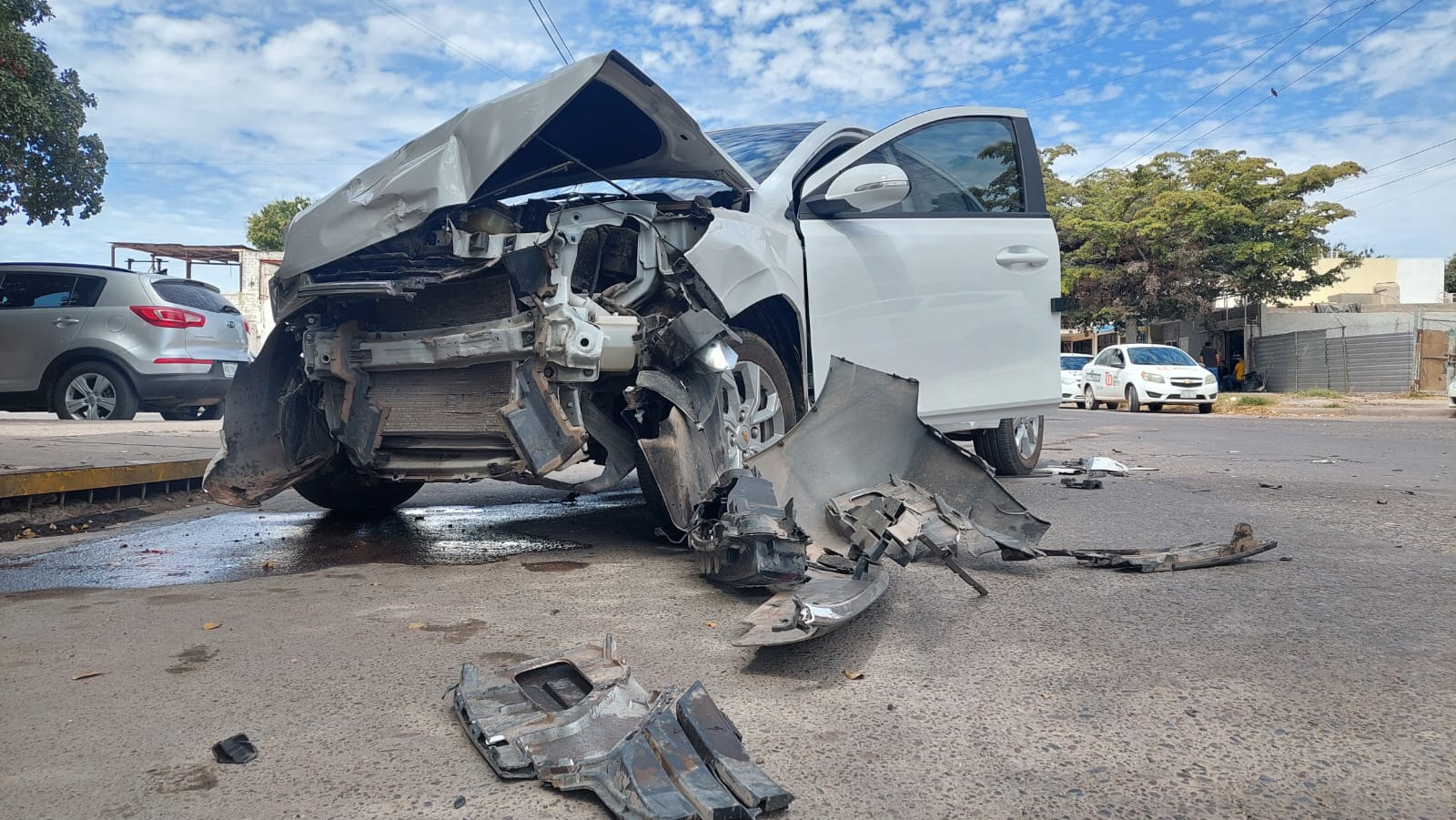 Chevrolet Aveo blanco destrozado de la parte frontal.