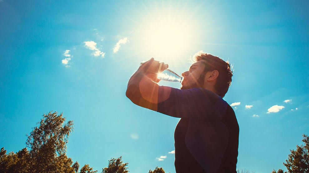 Persona tomando agua por el calor