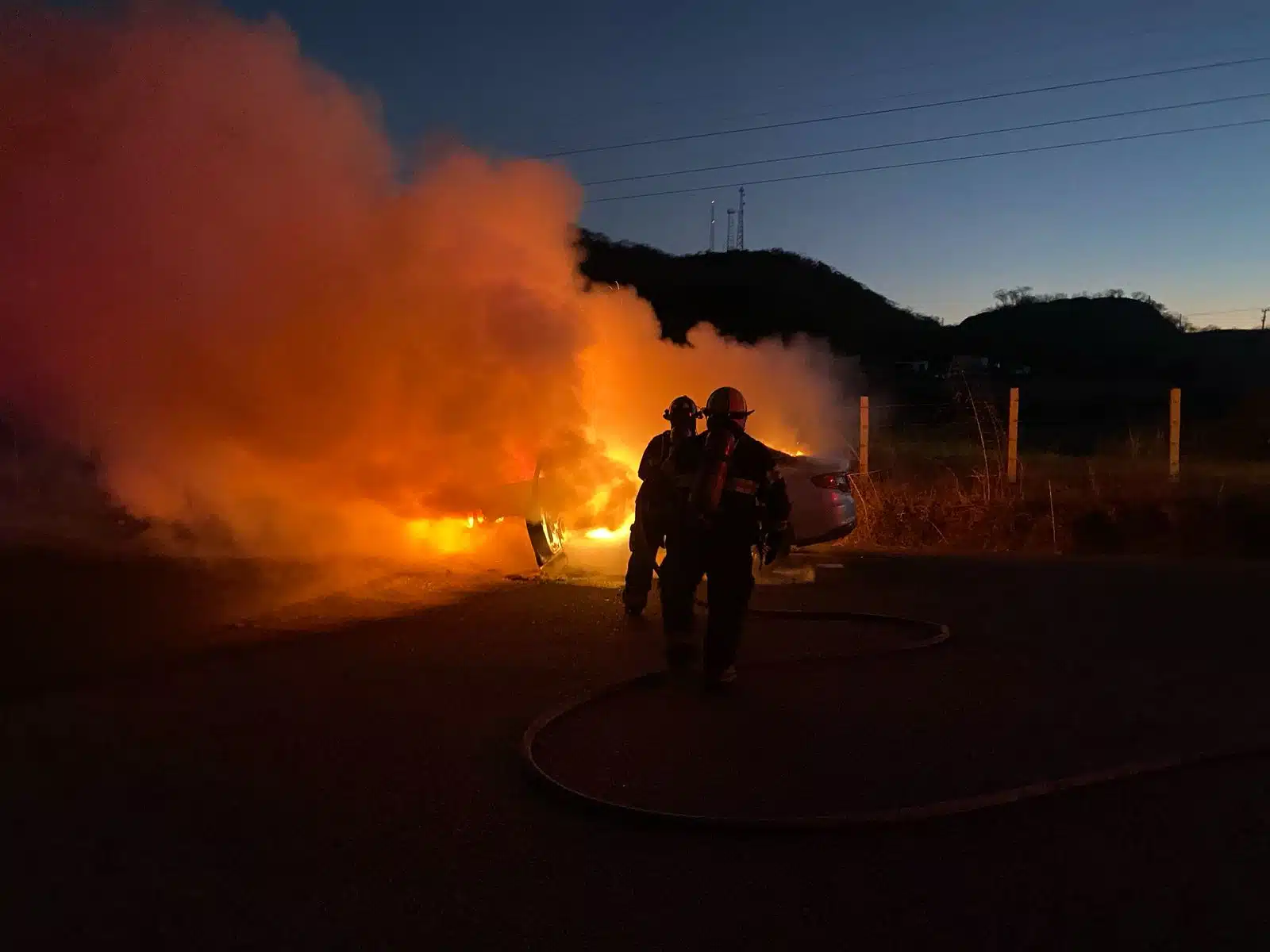 Bomberos intentan apagar el incendio sobre un automóvil