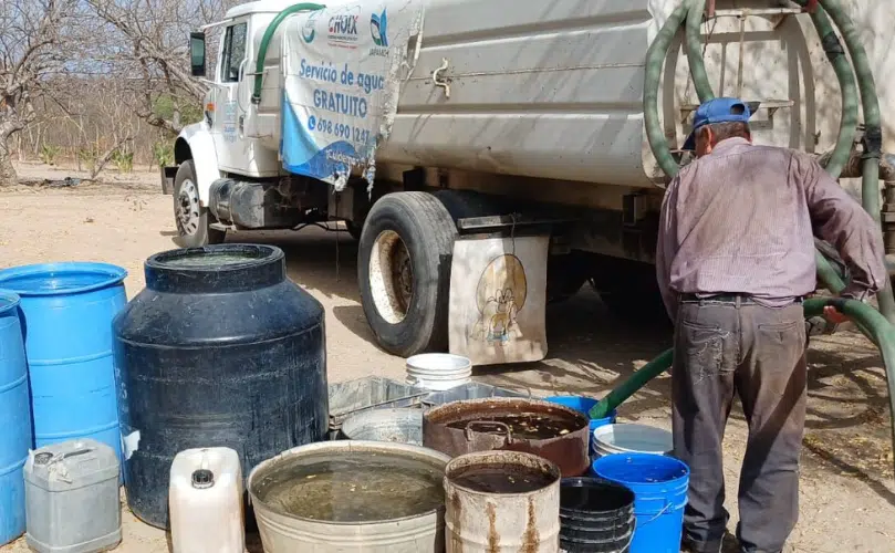 Un hombre llena varios botes de agua