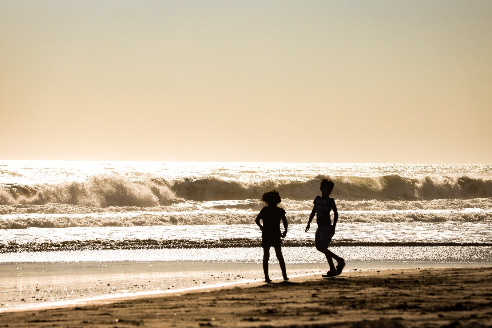 Niños disfrutando de la playa en un día caluroso.