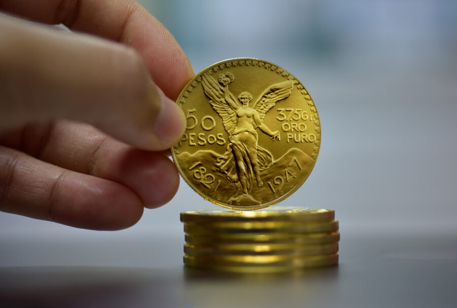 Monedas de Centenario y una mano tomando una moneda