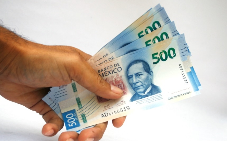 Una persona sosteniendo muchos billetes de 500 pesos mexicanos.