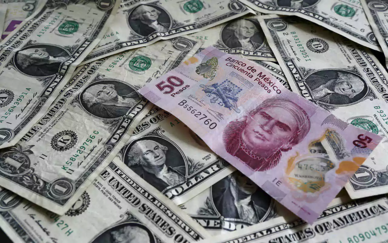 Un billete de 50 pesos mexicanos entre muchos dólares.
