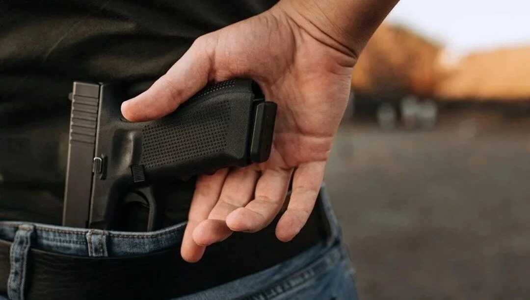 Hombre sacando un arma de sus pantalones.