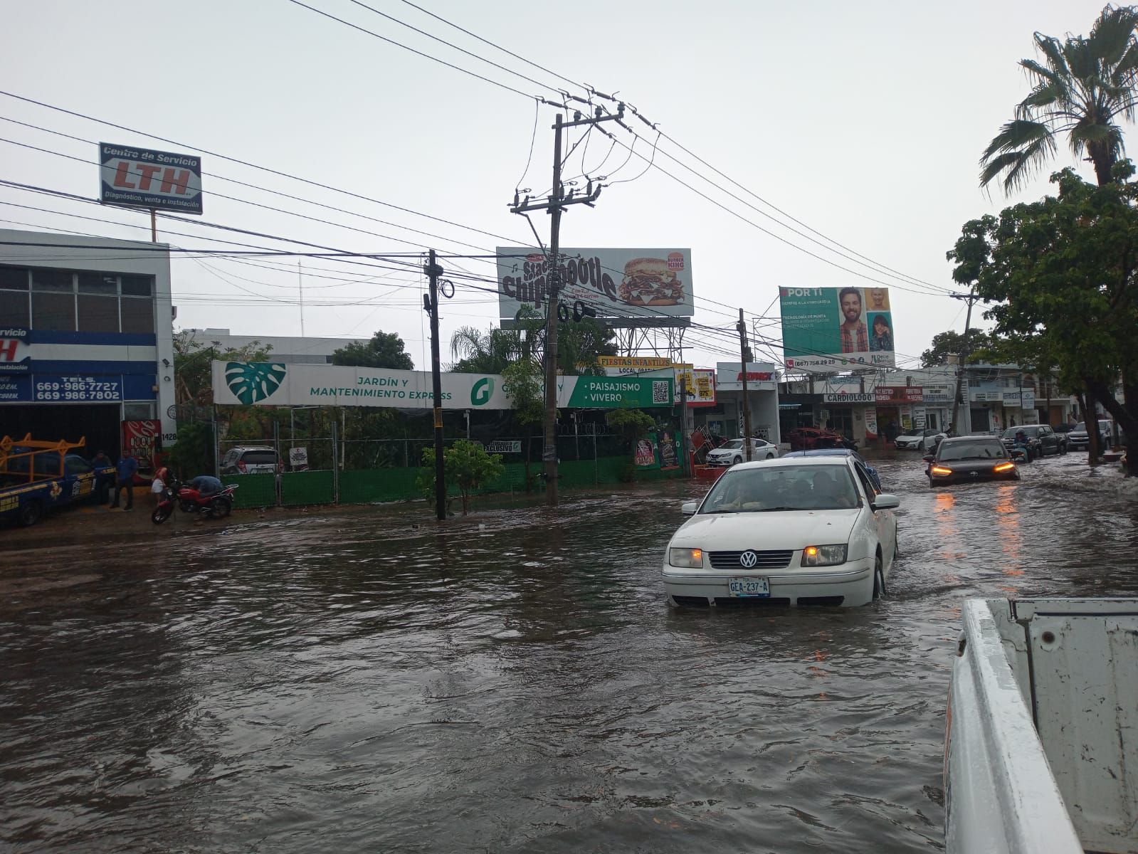 Carros circulando por una calle inundada en Mazatlán.
