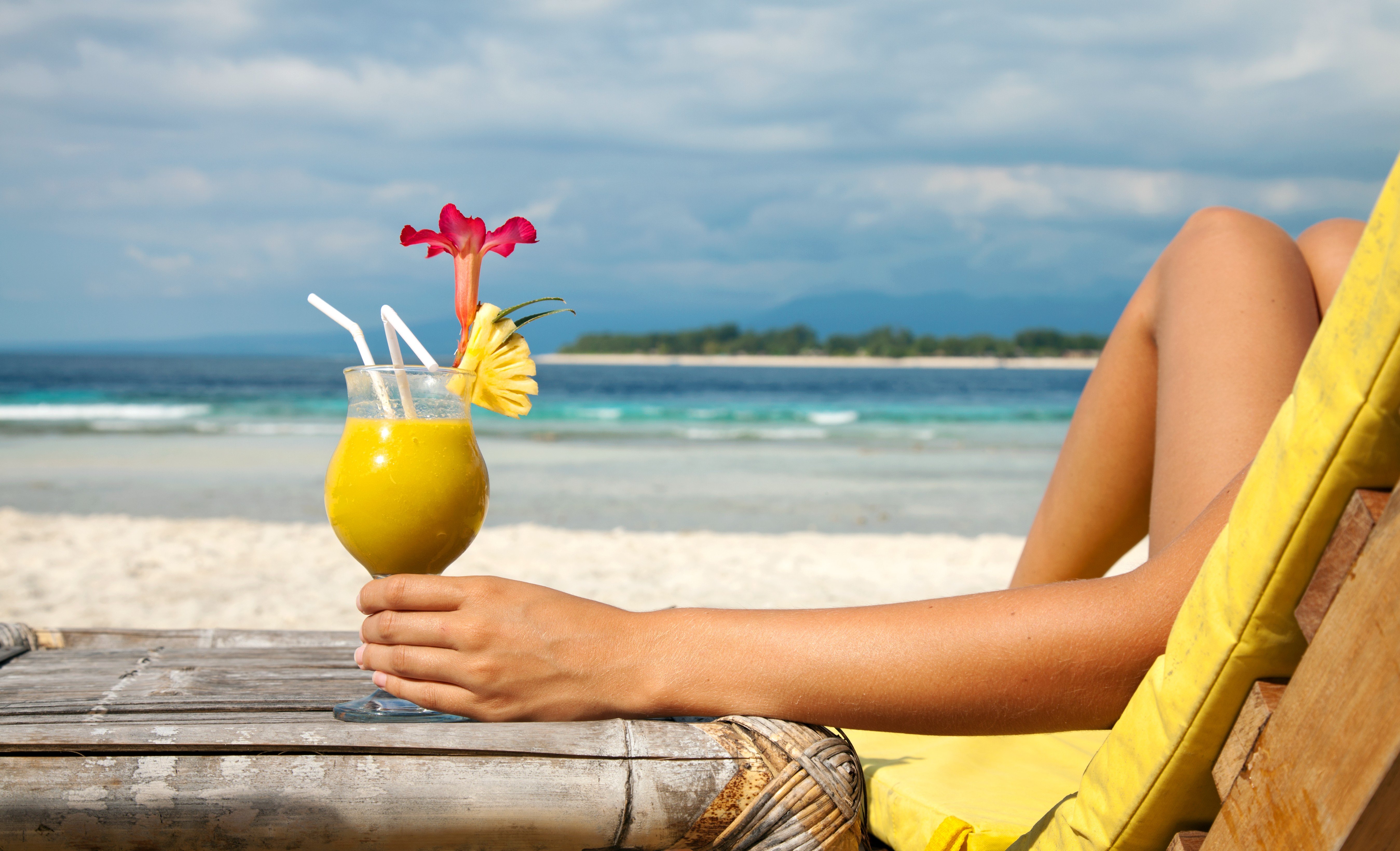 Persona sosteniendo una bebida refrescante en la playa.