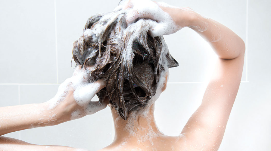 persona lavándose el cabello con shampoo