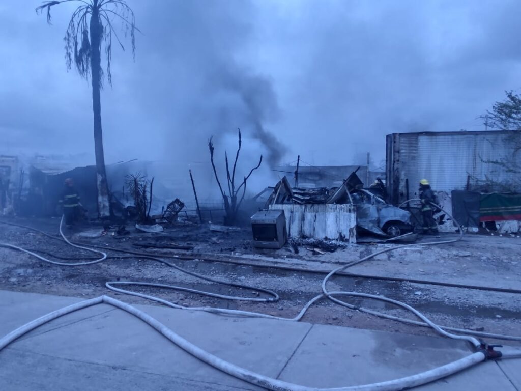Bomberos combatiendo el incendio en la pensión vehicular.