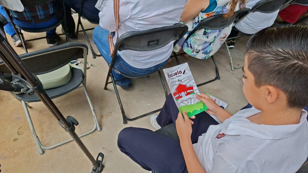 Alumno de la primaria “Profesor Marcos Mora Aguilera” sosteniendo un folleto informativo.
