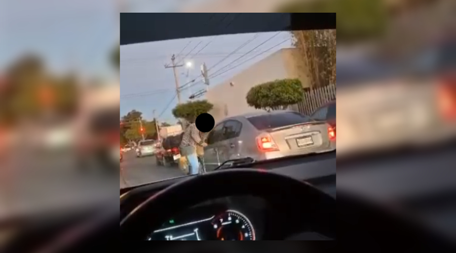 Motociclista agrediendo a una pareja al interior de un vehículo.