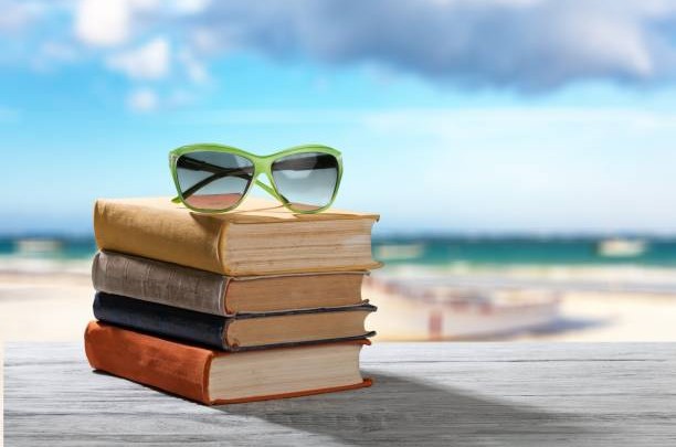 Libros y gafas en una playa de fondo.