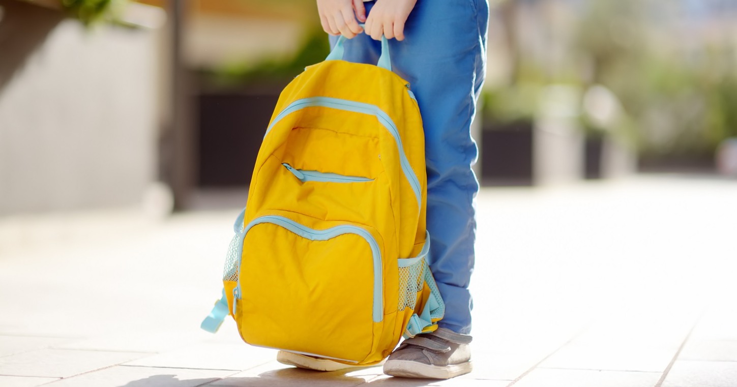 Niño sosteniendo su mochila escolar.