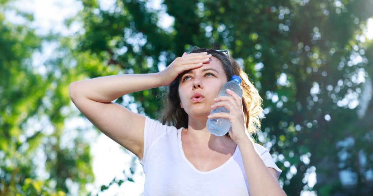 Mujer sosteniendo una botella de agua en un día caluroso.