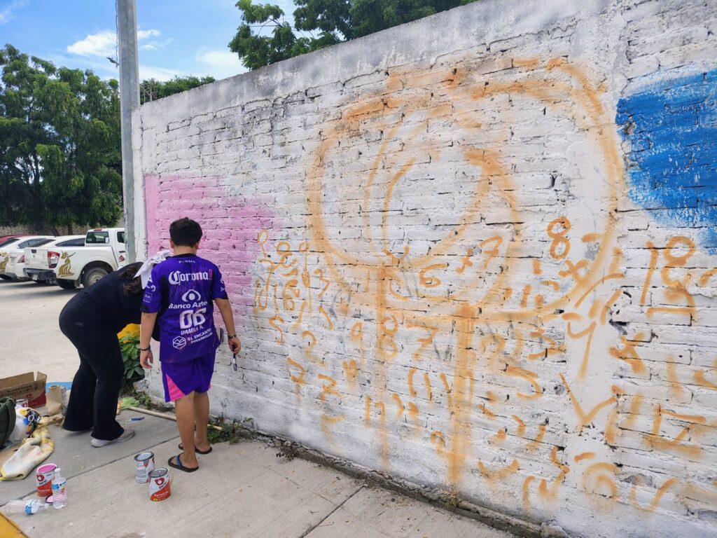 Jóvenes pintan paredes con murales